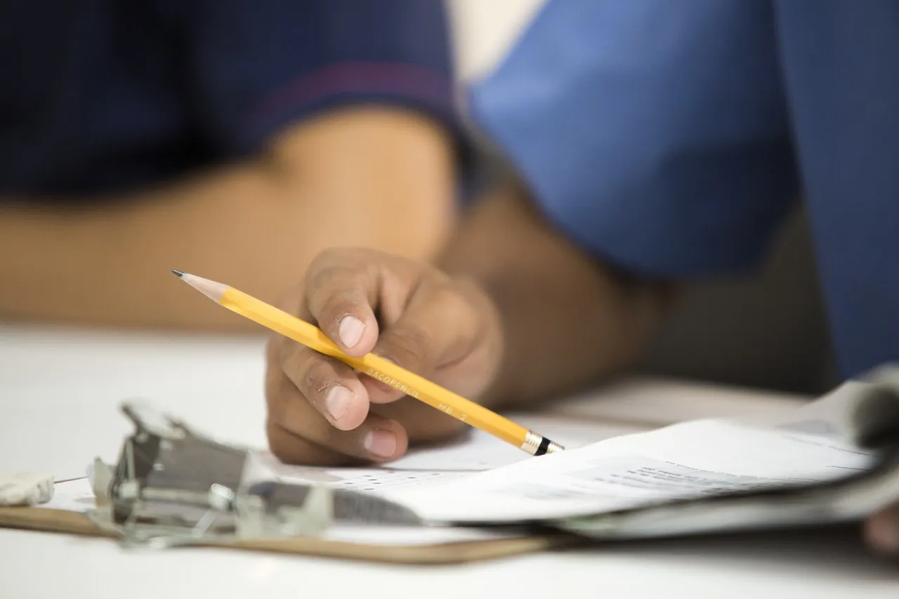 Photo showing pencil, hand, desk and paperwork.
