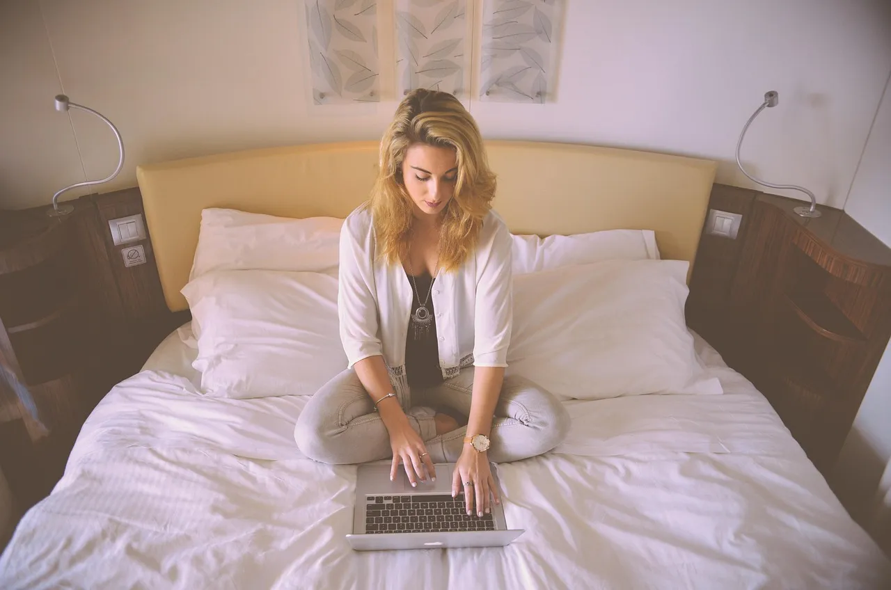 Photo showing woman, working, bed and laptop.