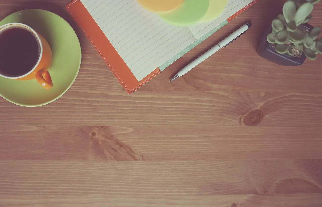 Photo showing coffee, notebook, wooden and orange.