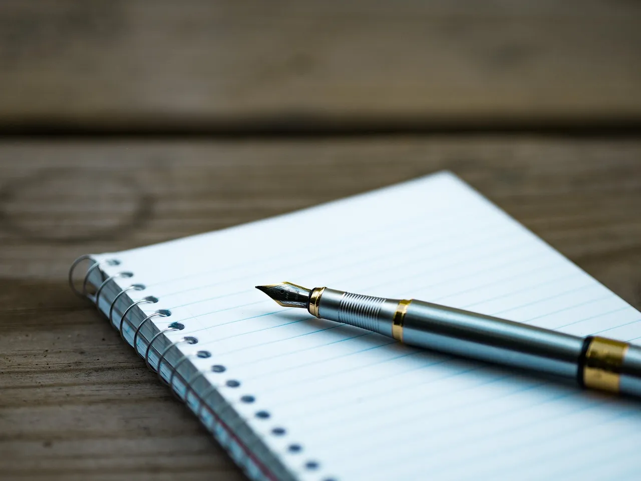 Photo showing fountain pen, note, notebook and page.